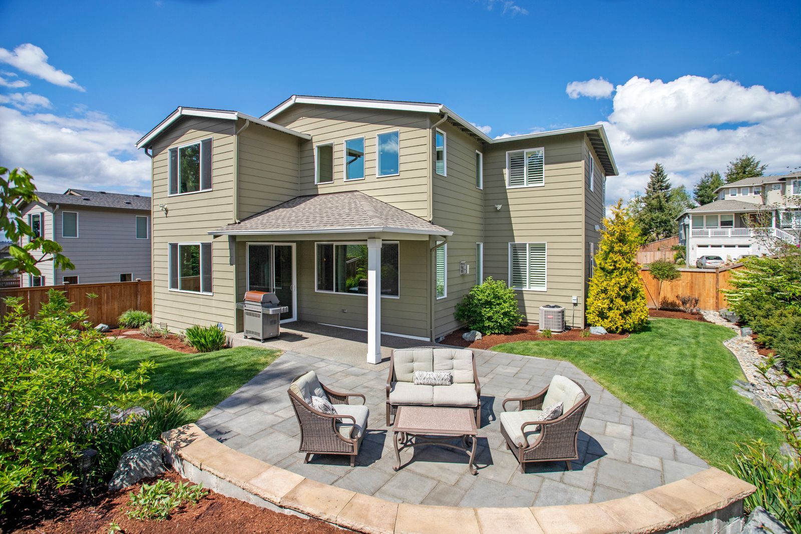 Sunny backyard with patio seating and landscaped borders