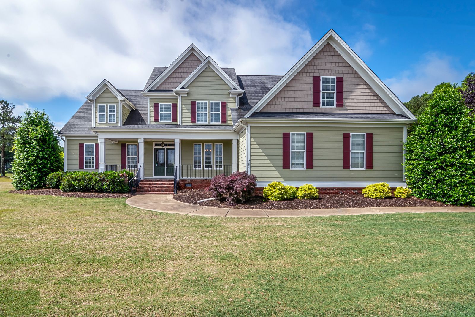 Two-story home with a manicured front lawn and covered porch